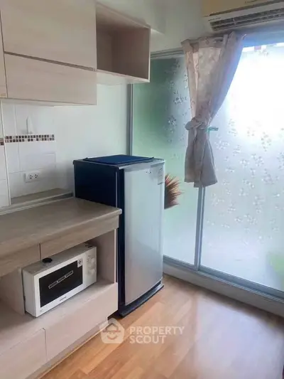 Modern kitchen with microwave and compact fridge, featuring frosted glass sliding door and wooden flooring.