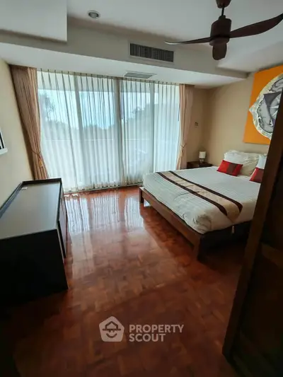 Spacious bedroom with large windows and elegant decor in a modern apartment.