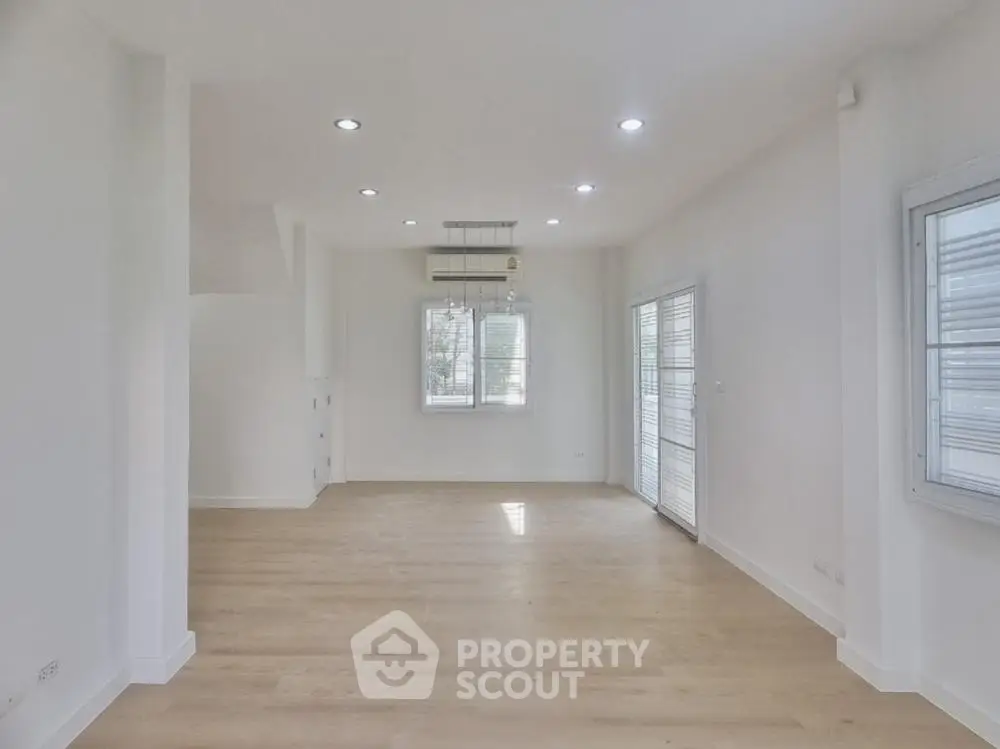 Spacious and modern living room with abundant natural light, sleek hardwood floors, and a versatile open layout perfect for customization.