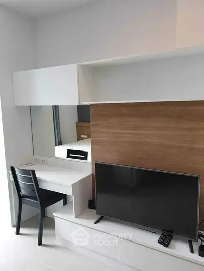 Modern living room with sleek TV setup and stylish desk area.