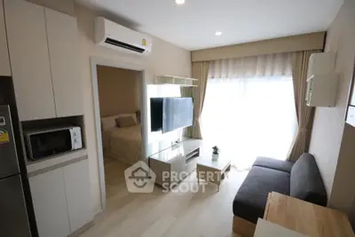 Modern living room with cozy sofa, wall-mounted TV, and natural light from large window.