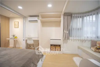Modern bedroom with study area and cozy seating by the window, featuring elegant decor and ample natural light.