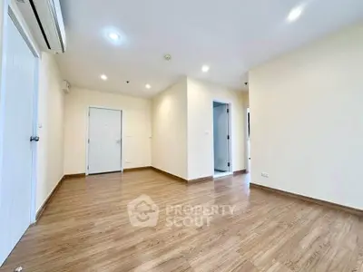 Spacious empty room with wooden flooring and bright lighting, ideal for customization.