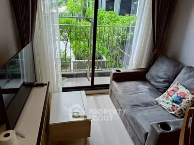 Cozy living room with balcony view, modern sofa, and entertainment setup.