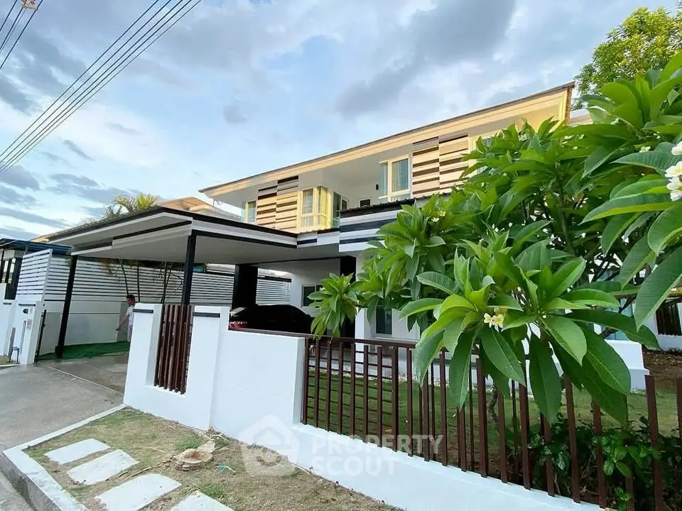 Modern two-story house with lush garden and carport in serene neighborhood