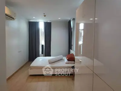Spacious bedroom with natural light and modern furnishings in a stylish apartment.