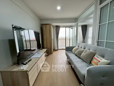 Modern living room with sleek TV and cozy sofa, featuring a balcony view.