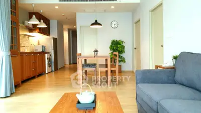 Spacious living room with modern kitchen and cozy dining area in open layout apartment.