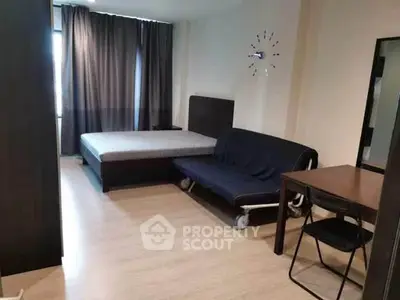 Modern studio apartment with bed, sofa, and dining table in a cozy setting.