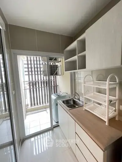 Modern kitchen with sleek cabinetry and washing machine in compact layout.