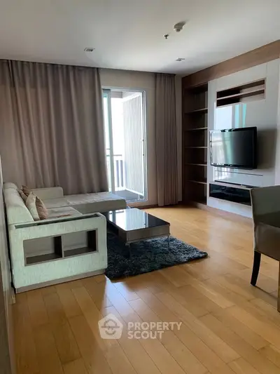 Spacious living room with modern decor and large TV, featuring a cozy sofa and wooden flooring.