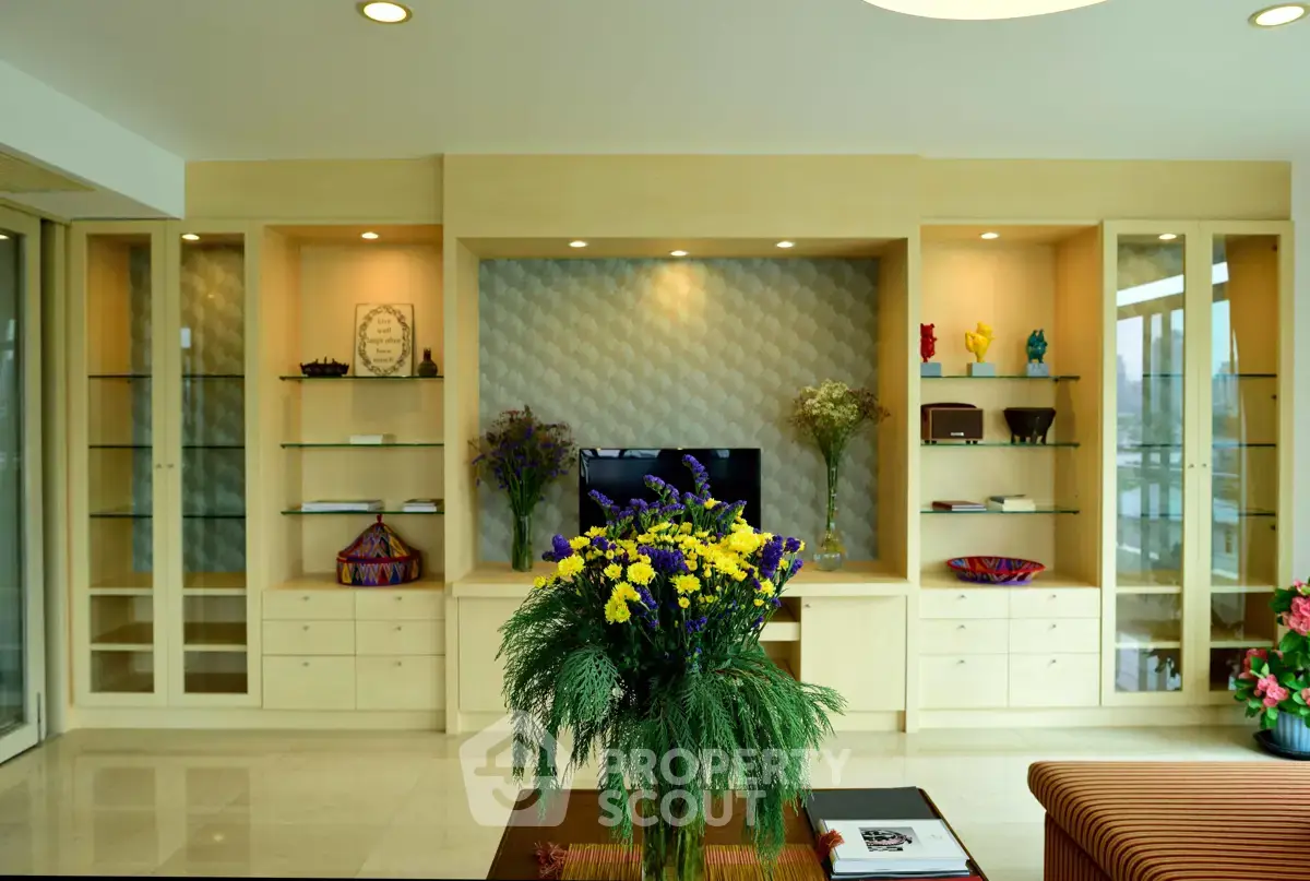 Elegant living room with built-in shelves and modern decor, featuring a vibrant floral centerpiece.