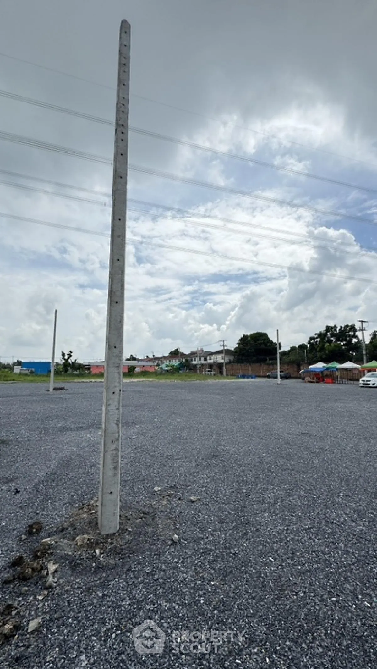 Spacious gravel parking lot with utility poles under a cloudy sky
