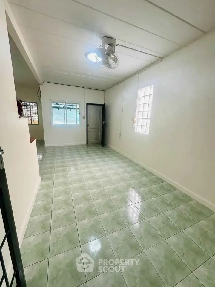 Spacious empty room with tiled floor and ceiling fan, ideal for customization.