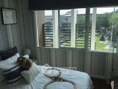 Charming bedroom with large window offering serene garden view, perfect for relaxation.