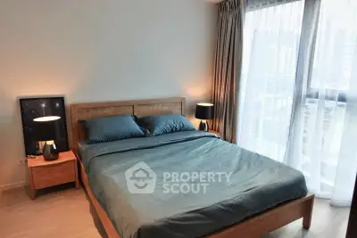 Modern bedroom with wooden bed frame and large window offering city view