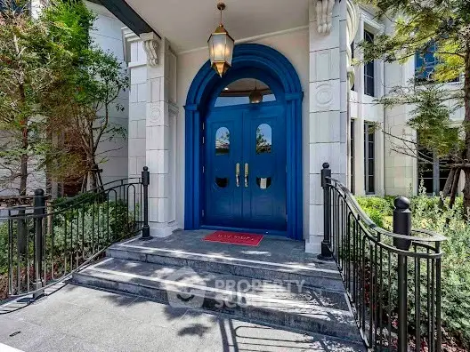 Elegant entrance with blue double doors and lush greenery, perfect for luxury living.