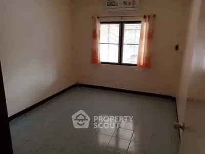 Spacious empty room with tiled floor and window, perfect for customization.