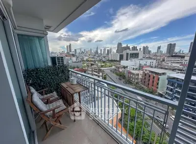 Stunning city view from a high-rise balcony with cozy seating area.
