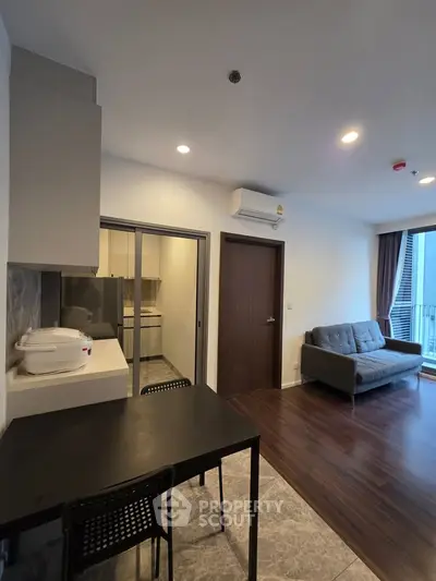 Modern apartment interior with open kitchen and cozy living area, featuring sleek furniture and natural light.