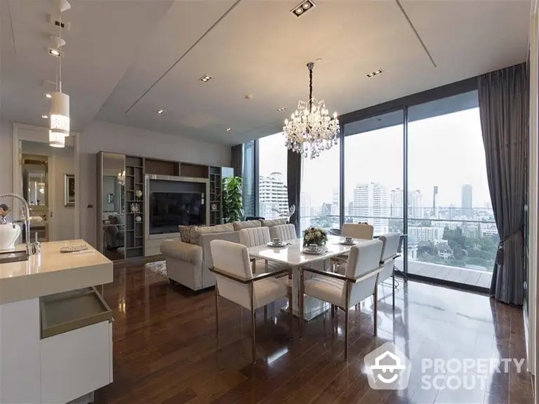 Luxurious open-plan living space with gleaming hardwood floors, elegant chandelier, and panoramic city views through floor-to-ceiling windows.