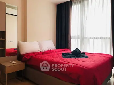 Cozy bedroom with red bedding and natural light from large window