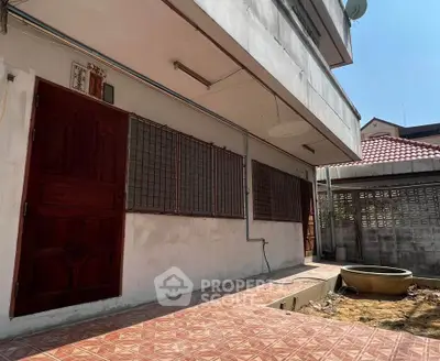 Spacious exterior view of a residential property with tiled patio and red door, perfect for outdoor activities.