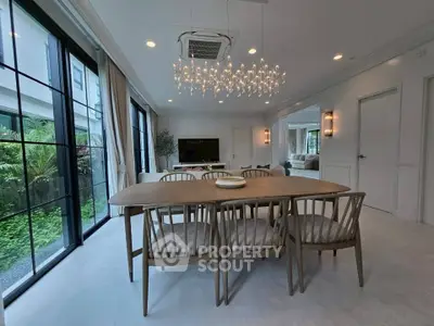 Spacious modern dining area with elegant chandelier and garden view, perfect for entertaining.