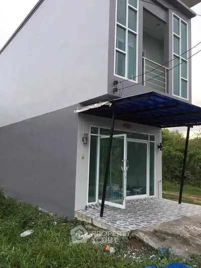 Modern two-story building with glass entrance and balcony, ideal for residential or commercial use.