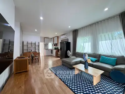 Spacious modern living room with open kitchen, stylish decor, and natural light.