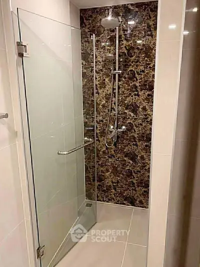 Modern bathroom with elegant glass shower and marble wall design.