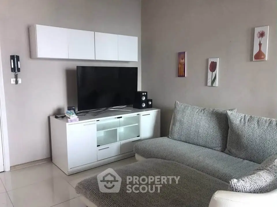 Modern living room with sleek white furniture and large TV, perfect for relaxation and entertainment.