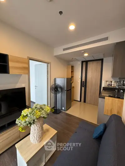 Modern living room with sleek design, featuring a cozy sofa, stylish decor, and compact kitchen area.
