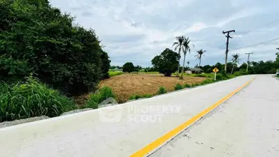 Scenic view of a rural road with lush greenery and open fields, perfect for countryside living.