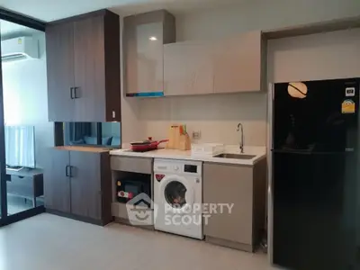 Modern kitchen with washing machine and sleek cabinetry in a stylish apartment.