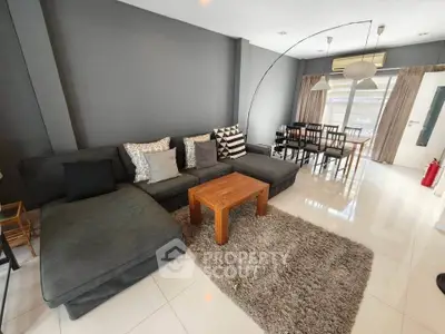 Spacious living room with modern decor and dining area, featuring a cozy sectional sofa and stylish wooden table.