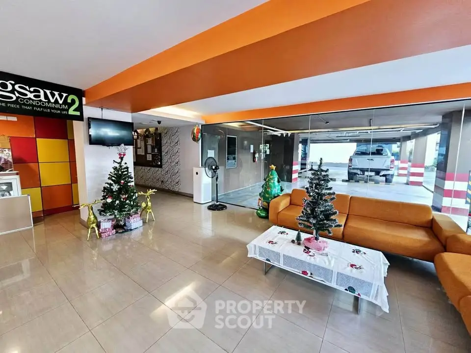 Modern condominium lobby with festive decor and vibrant orange accents.