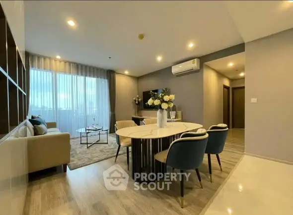Modern living room with elegant dining area and cozy seating, featuring stylish decor and ambient lighting.