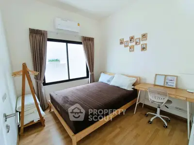 Cozy bedroom with wooden flooring, modern decor, and ample natural light.