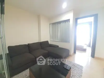 Cozy living room with sectional sofa and glass coffee table, adjacent to a bright bedroom.