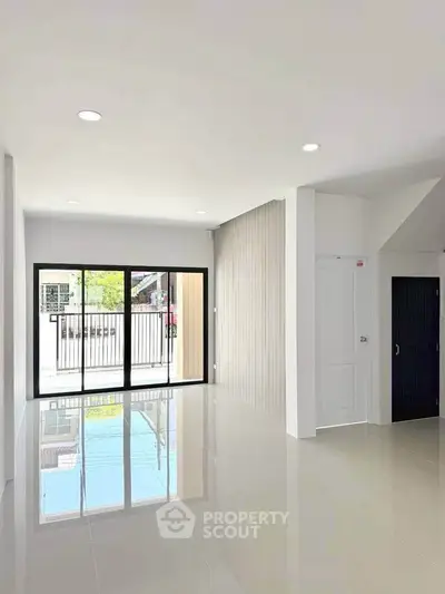 Spacious modern living room with large windows and glossy tiled floors