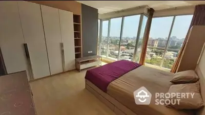 Spacious bedroom with large windows offering panoramic city views, modern design, ample storage, and natural light.