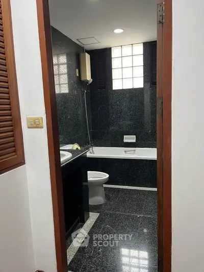 Elegant black-tiled bathroom with bathtub and modern fixtures