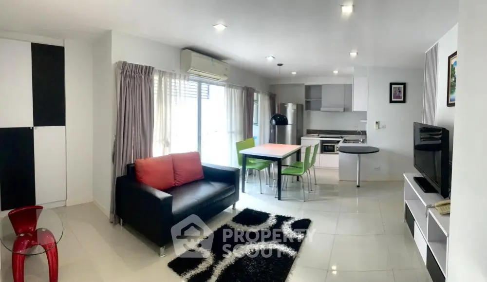 Modern open-plan living room with stylish furniture and kitchen area, featuring sleek design and ample natural light.