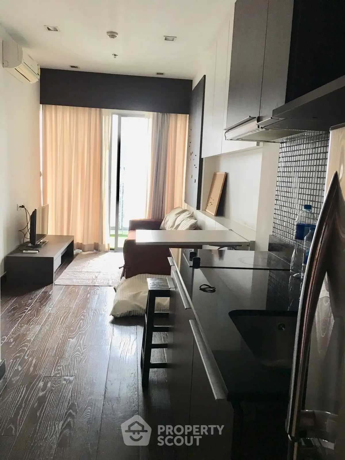 Modern apartment with open layout kitchen and cozy living area, featuring sleek design and natural light.