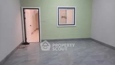 Spacious unfurnished room with green accent wall and tiled flooring