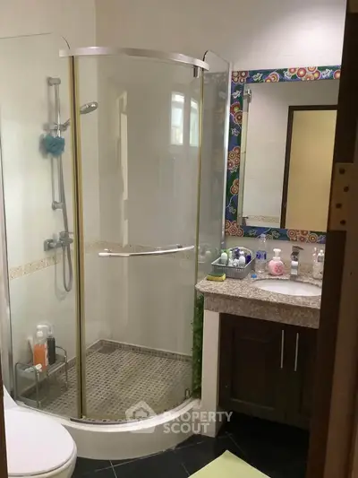 Charming bathroom with modern shower and colorful mirror frame, perfect for a cozy home.