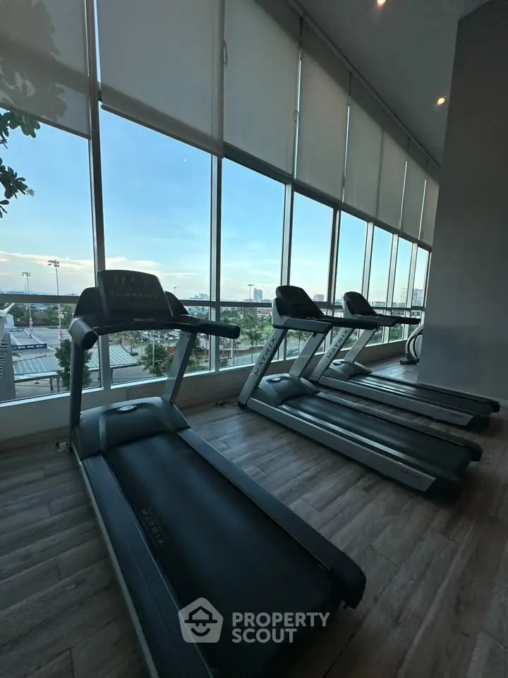 Modern gym with treadmills and large windows offering a scenic view, perfect for fitness enthusiasts.