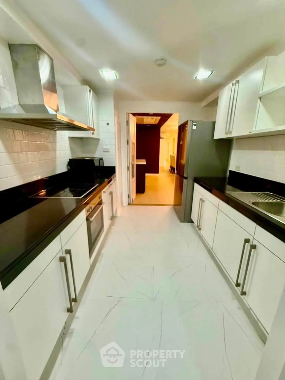 Modern kitchen with sleek black countertops and stainless steel appliances in a spacious apartment.