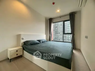 Modern bedroom with large window and city view in high-rise apartment.